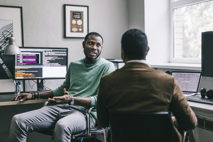 Two programmers having a chat at their workplace.