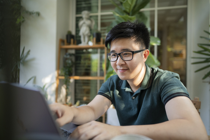 Young Man Using Laptop At Home With Plants.