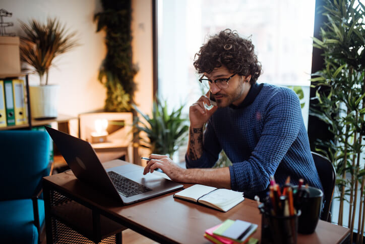 Male business professional taking a call at his office desk.