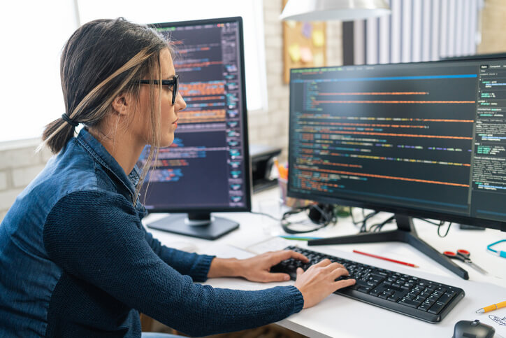 Female software developer coding on her desktop machine at the office.