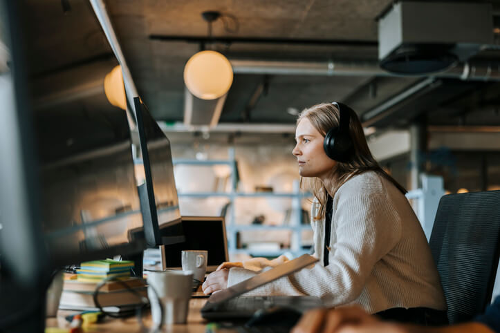 Focused female IT support professional coding on her desktop computer while sitting at her desk in the office.