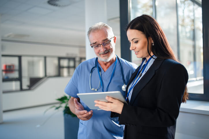 Female healthcare manager chatting about reports with a senior male doctor in a hospital.