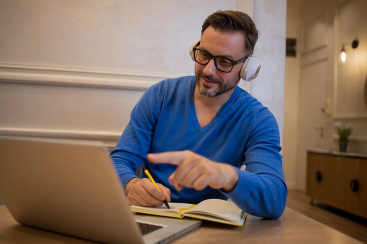 Mid adult man chatting with his professor online at home.