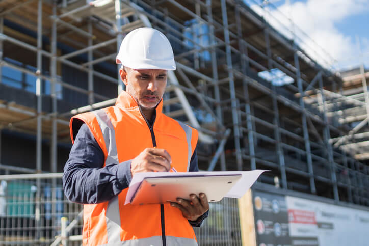 Civil engineer in protective clothing on worksite with digital blueprints.