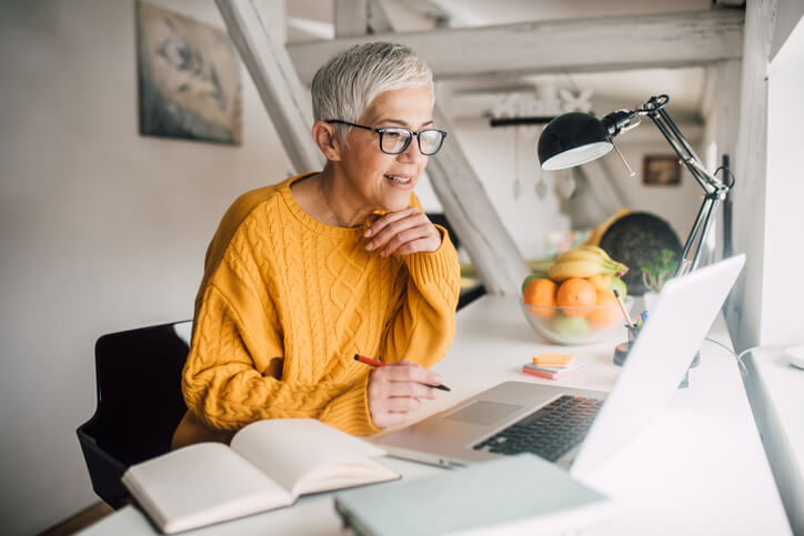 Older woman working on laptop at home.