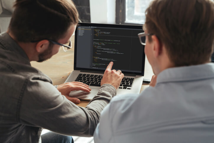 Over the shoulder view of coders working on a new project together.