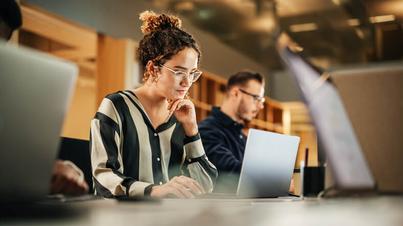 Female Asian software programmer working at her desk at a startup company.
