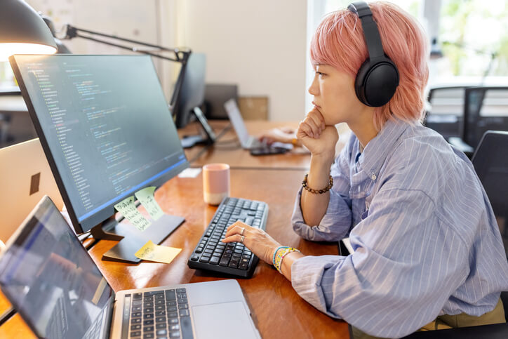 Female Asian software programmer working at her desk at a startup company.