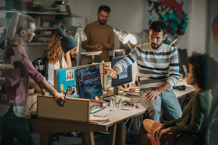 Group of computer programmers talking while working in the office.