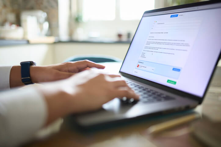 Close-up of man attaching his resume while applying for a job offer online with his laptop from home.