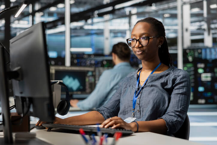 Black female database programmer analyzing software metrics on her office computer.