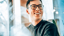 Asian entrepreneur wearing glasses, smiling and looking forward to his future startup innovations.